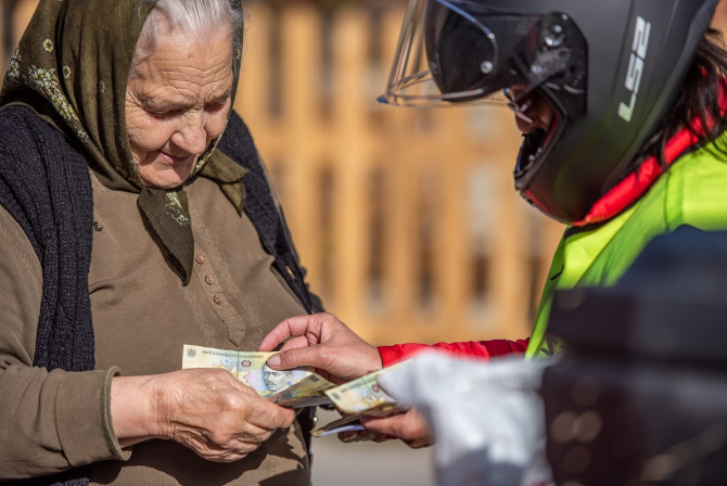 Pensionară primind venitul cuvenit / FOTO: Pagina de Facebook a Poștei Române