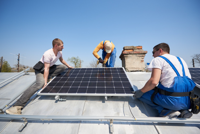 Muncitori montează panouri solare pe acoperișul unei case / Freepik
