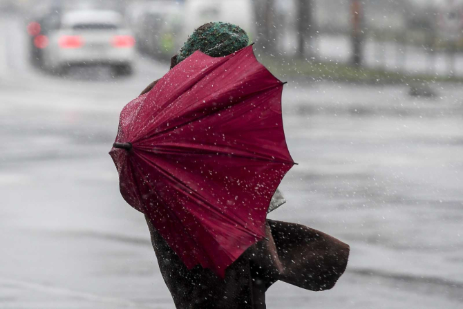 O persoană se apără de vijelie și ploaie cu o umbrelă